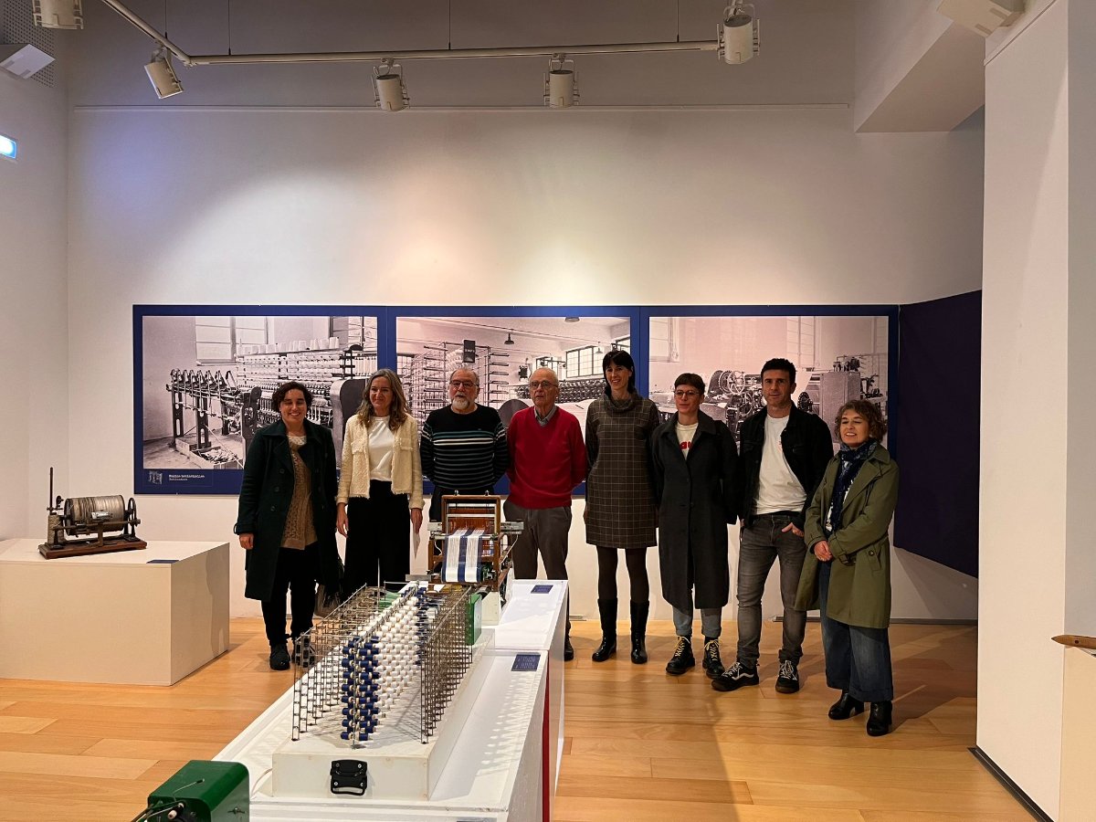Grupo de visitantes en la exposición del Museo Laboratorium de Bergara junto a una instalación de la exposición sobre proceso textil.