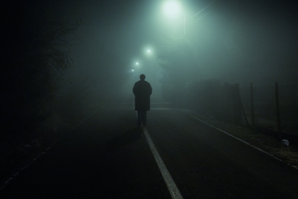 Hombre solo en una carretera neblinosa.