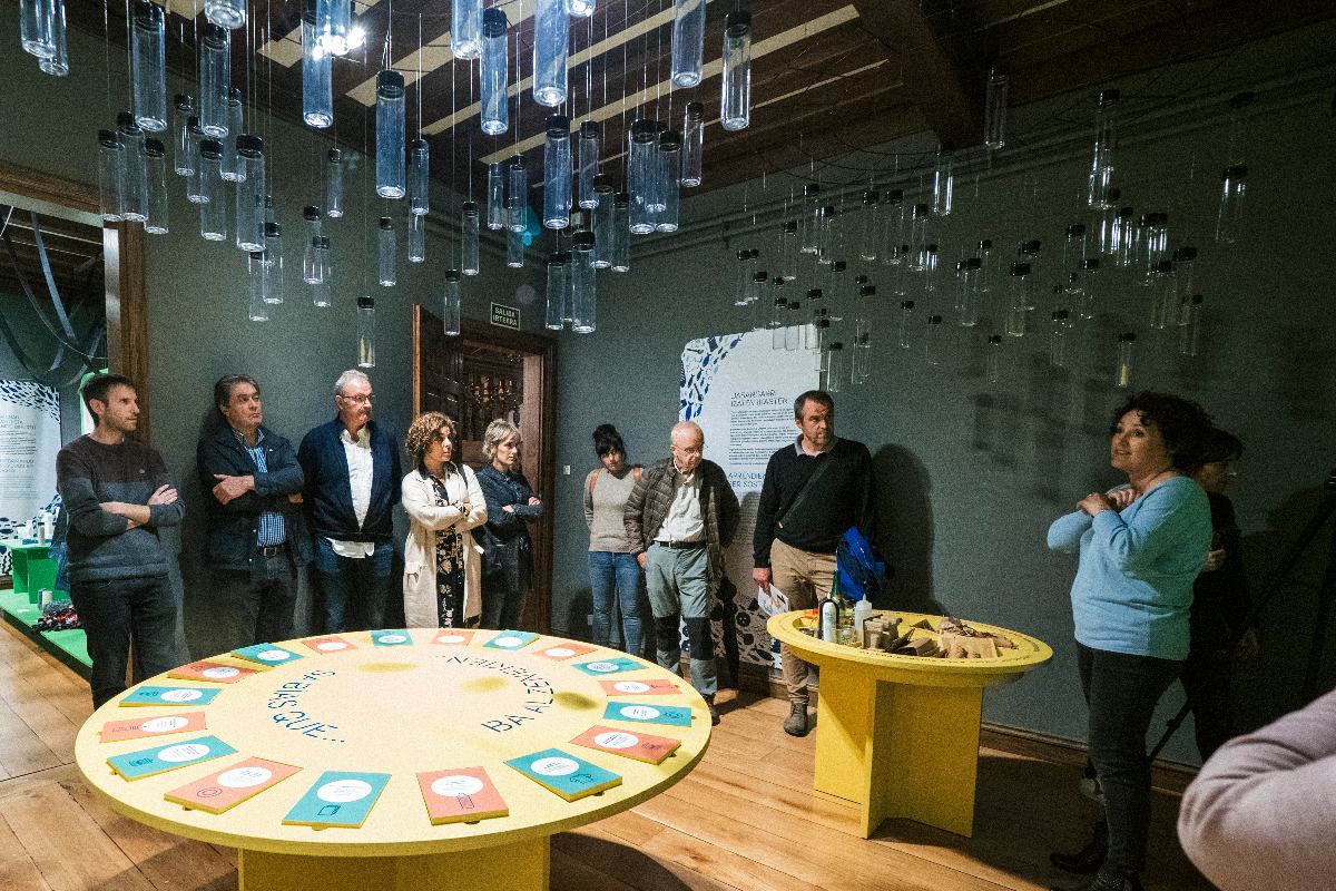 Grupo de visitantes en actividad guiada en la exposición del Museo Laboratorium de Bergara con instalación interactiva sobre sostenibilidad.